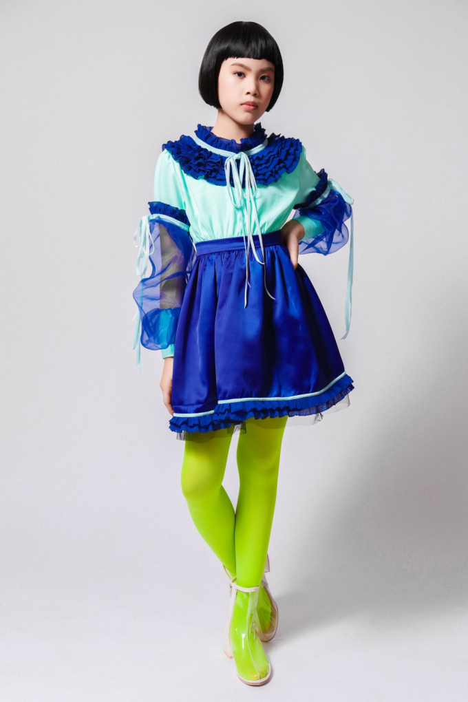 Bộ sưu tập sử dụng chất liệu chính là lụa phối voan lưới và chiffon. Chi tiết thắt nơ và những đường bèo nhún viền quanh cổ áo, tay áo hay chân váy giúp bé gái thêm điệu đà.