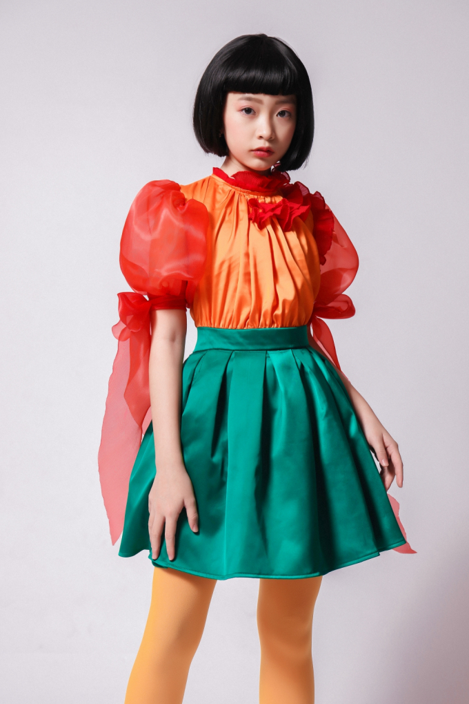 Phom dáng cocktail đơn giản không nhàm chán nhờ phần chân váy xếp ly và tay áo phồng cổ điển. Tóc ngắn “maruko” với phần mái bằng ngắn cho các mẫu nhí vẻ ngoài vừa đáng yêu, vừa cá tính.